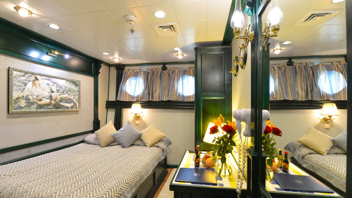 cabin interior with bed, coffee table, wine, fruits, mirror