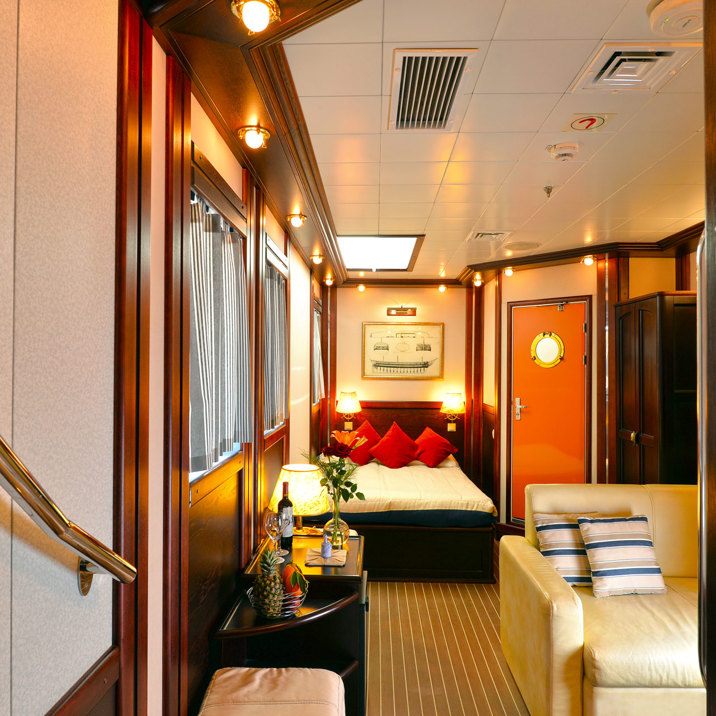 cabin interior with sofa, bed, and wine and flowers on the table