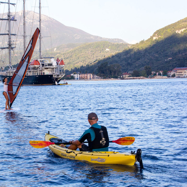 windsurf and kayak in front of the ship next to island