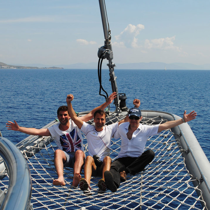 three crew members on the ship nose on the net waving