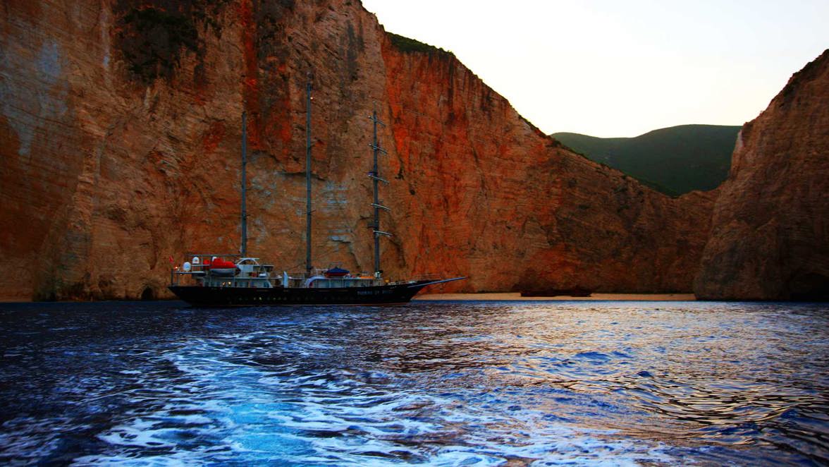 ship at the coast next to red rocks