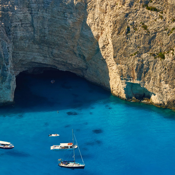 boats next to rocky coast with caves