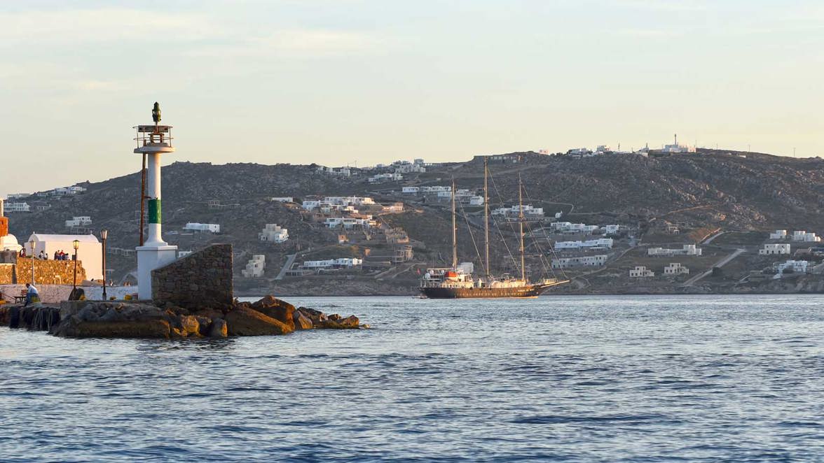 ship next to coast town and lighthouse