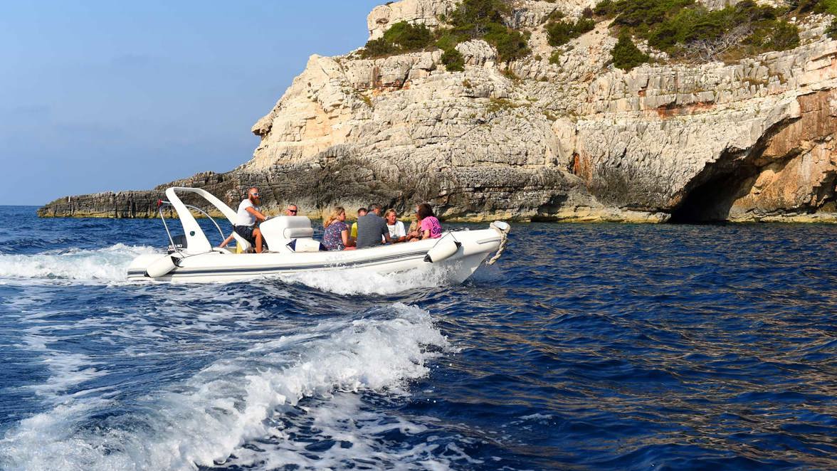 tender and guests next to rocky coast caves