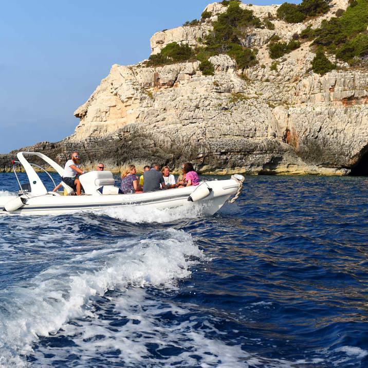 tender and guests next to rocky coast caves