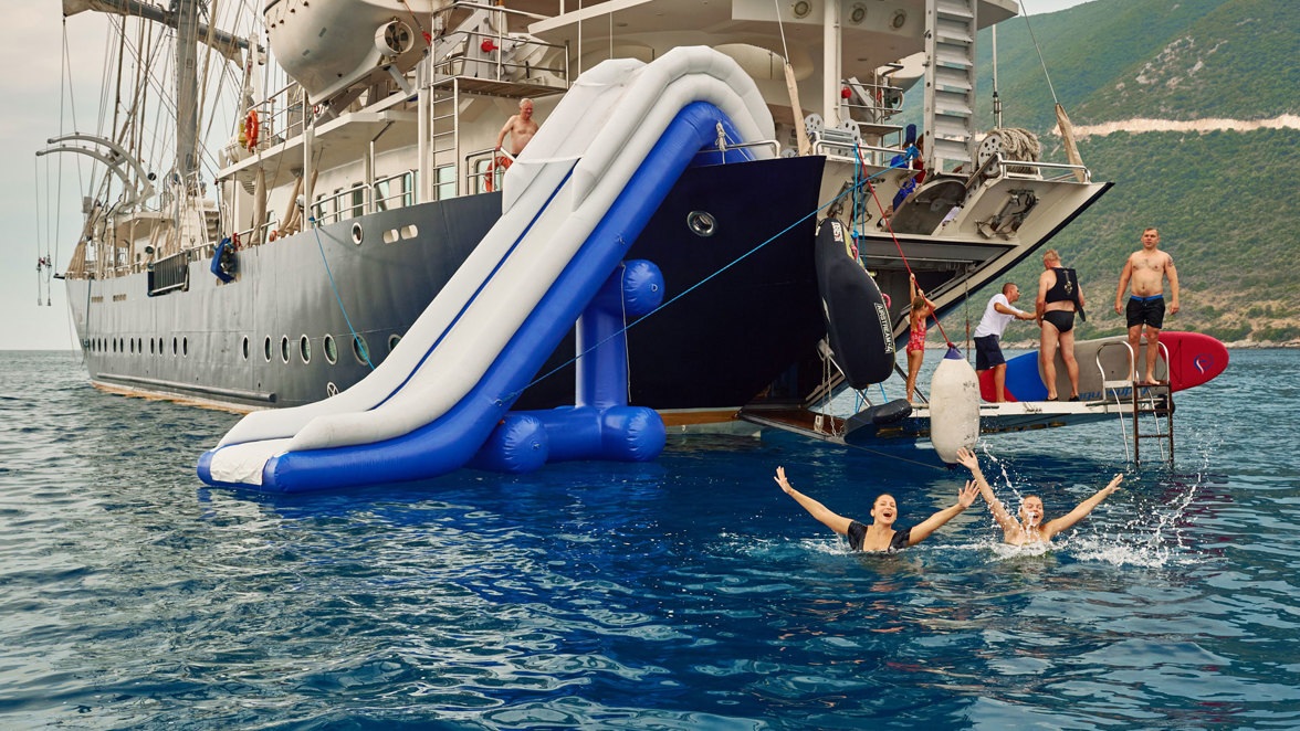 guests swimming next to ship with water slide and open apparel