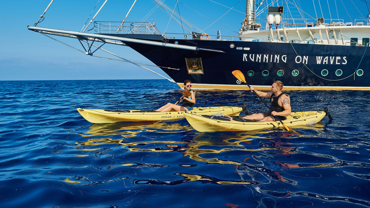 guests kayaking next to ship